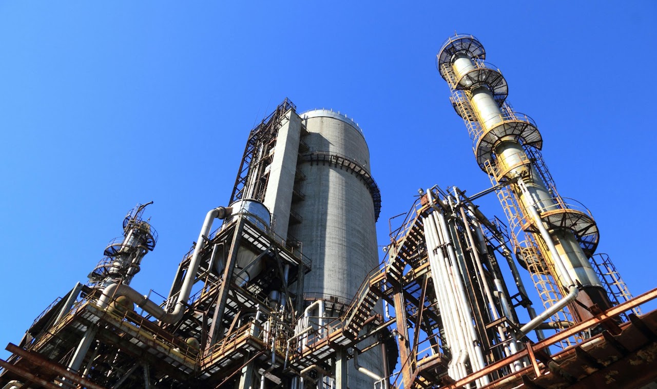Industrial processing towers and pipework beneath a clear blue sky